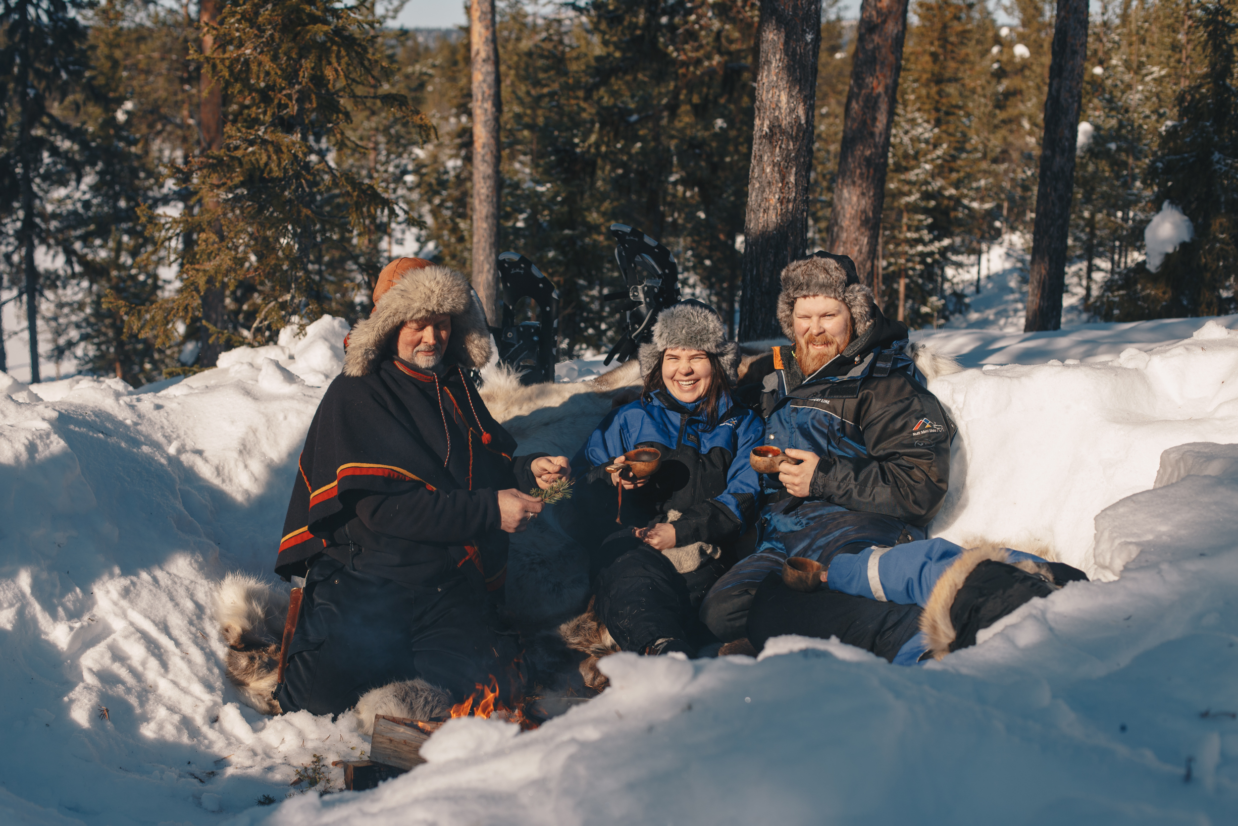 en guide med två turister fikar i snön
