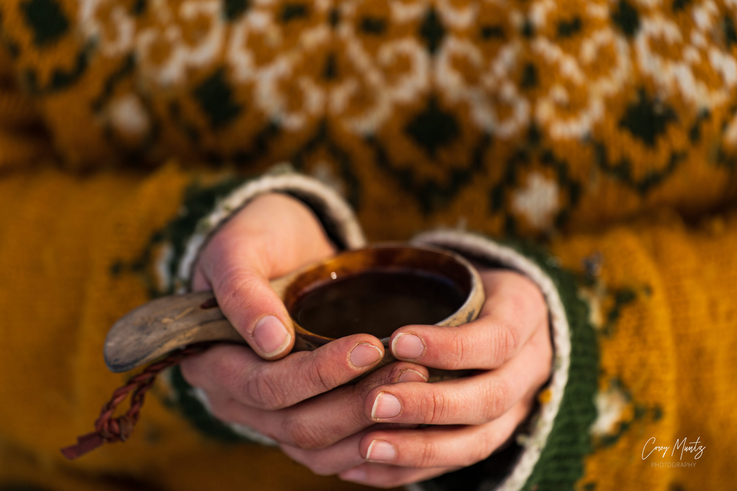 samisk kåsa hålls av kvinna i stickad tröja